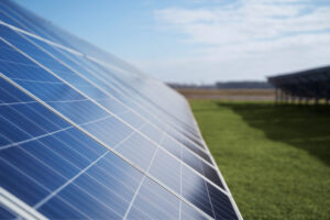 Solar panels tilted in a sunny field under a blue sky, capturing sunlight for energy generation